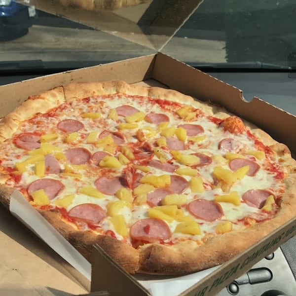 A Niki's Pizza & Pasta Hawaiian pizza with ham and pineapple in a cardboard box.