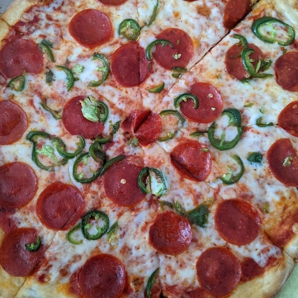 Close-up of a Niki's Pizza & Pasta pepperoni pizza with sliced jalapeños.